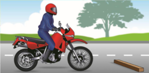 Image of a motorcycle on the roadway with a piece of wood blocking the lane